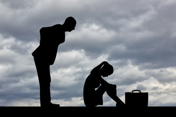 Wall Mural - Silhouette of a standing man leaned over a woman who is sitting on the floor, clasping her legs against a cloudy sky