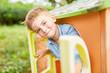 Boy mischievously looks out of the playhouse
