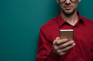 Wall Mural - Portrait of a positive young man in glasses with phone