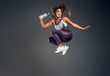 © Fxquadro - Exited cheerful woman is jumping at studio while holding the bottle of water over grey background.