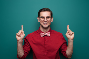 Wall Mural - Portrait of a cute young man showing fingers on a green background