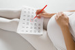 Young pregnant woman marking childbirth day in calendar. Baby expecting concept. Planning of future.