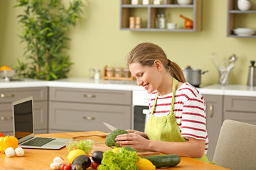 Wall Mural - Beautiful young woman cooking in kitchen