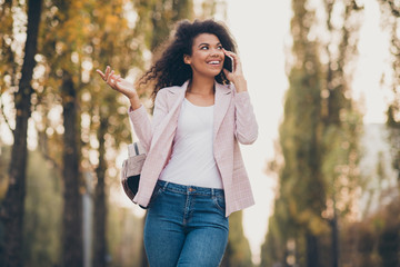 Wall Mural - Photo of amazing pretty dark skin lady spending time walk park after university lectures hold telephone speak best friend autumn weather wear jacket jeans outdoors