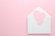 Paper hearts in envelope on pink background, top view. Space for text