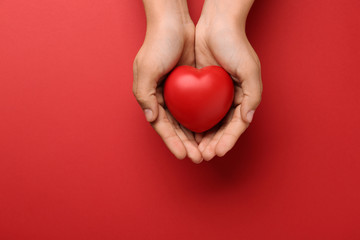 Poster - Woman holding decorative heart on red background, top view