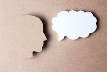 Head Silhouette With Speech Bubble On Brown Paper Background.