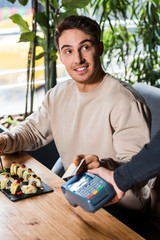 Wall Mural - selective focus of handsome man holding credit card near credit card reader