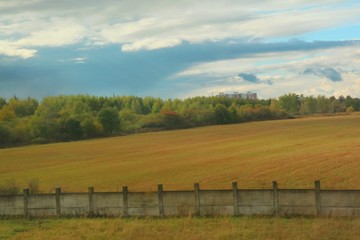 Wall Mural - Soft focus of country side view with colorful field and colorful leave on tree in autumn. View from running car's window. Nature and outdoor concept.