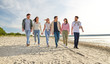 © Syda Productions - friendship, leisure and people concept - group of happy friends walking along beach in summer
