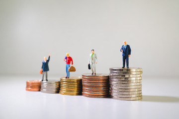 Miniature people, group of businessman standing on stack coins using as business and financial concept