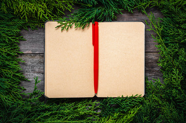 Wall Mural - Christmas frame from fir branches on a background of an old gray board around an open notebook with blank sheets. Frame of fir branches. Christmas card blank concept.