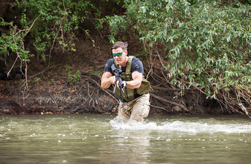 One day commando - wades through the water with a rifle