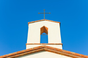 Old italian little church with metal Christian cross on the top against a sky - concept image with copy space