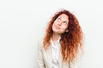 Young natural redhead business woman isolated against white background dreaming of achieving goals and purposes