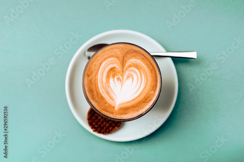 Photographie high angle view and close up of a cappuccino cup with teaspoon and cookie agains