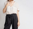 © oprzybysz - Young woman wearing simple stylish outfit with a neutral shirt and black trousers isolated on light grey background. Copy space