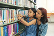 © sutlafk - Asia mother and daughter picking a book in public library