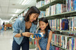 © sutlafk - Asia mother and daughter picking a book in public library
