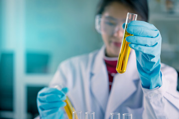 Young Asian medical technologist female making testing with test tube while doing research in science laboratory