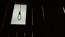 Loop neck of suicide from old rope hanging wooden background. Dark cloudy day loop horror sway from wind close up on square for gallow hangman 4K. Scary gallows time Inquisition stand on Halloween.