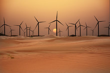 Wind Turbines In The Desert Suggesting Renewable Energy Concept With Sand Dunes At Sunset