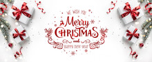 Merry Christmas Text On White Background With Gift Boxes, Ribbons, Red Decoration, Fir Branches, Bokeh, Sparkles And Confetti. Xmas And New Year Greeting Card, Bokeh, Light. Flat Lay, Top View
