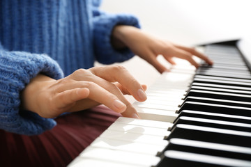 Young woman playing piano at home, closeup