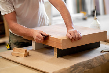 Canvas Print - Carpenter sanding the edge of a wooden block
