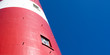detail of a red and white lighthouse with blue sky in the background