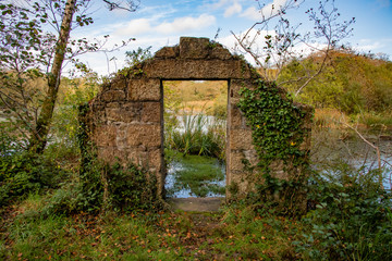 View of a peaceful lake seen through the doorway of a ruined building