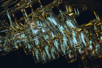 Clean washed and polished glasses hanging over a bar rack.