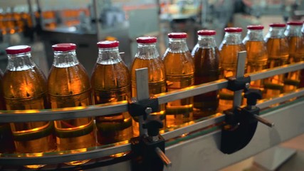 Wall Mural - Conveyor belt, juice in glass bottles on beverage plant or factory interior, industrial manufacturing production line