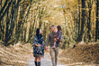 © Олег Кошевський - Beautiful young family walking in the autumn forest. Family walking in an autumn park with fallen fall leaves. Warm autumn