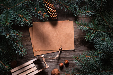 Wall Mural - Christmas frame from fir branches on a background of an old gray board around an open notebook with blank sheets. Frame of fir branches. Christmas card blank concept.