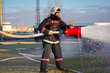Fireman with fire extinguishing foam spraying hose