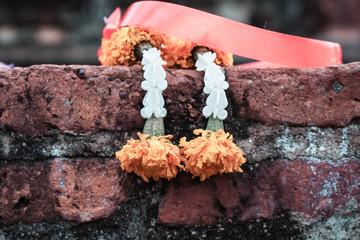 Wall Mural - Withered Jasmine Garland or steering flower on old brick in ancient Asian temple outdoor Fresh Orchid Handicraft Steering garland has rose crown flower Jasmine Dahlia Marigold colorful is very beautif