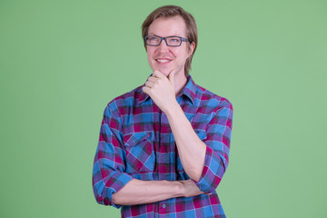 Wall Mural - Happy young handsome hipster man with eyeglasses thinking