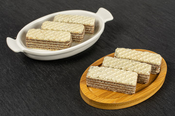 Sticker - Group of six whole crispy beige hazelnut wafer cookie in white oval ceramic bowl on bamboo coaster on grey stone