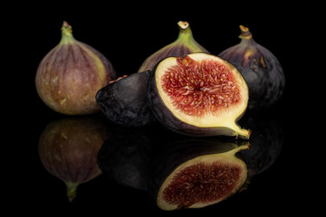 Group of three whole two halves of sweet purple fig isolated on black glass