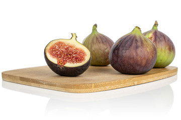 Group of three whole one half of sweet purple fig on bamboo cutting board isolated on white background