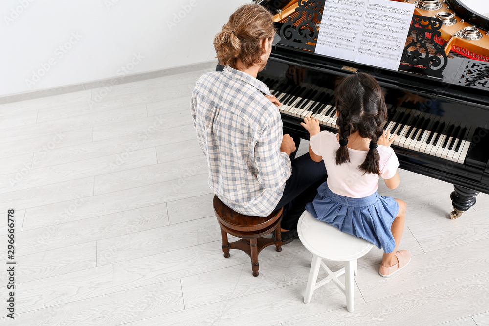 Man teaching little girl to play piano