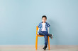 © Pixel-Shot - Cute fashionable boy sitting on chair against color wall