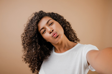 lovely happy black young woman making selfie isolated over brown