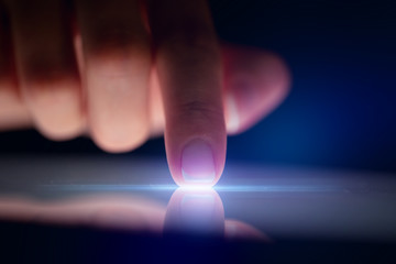Poster - Finger touching tablet with dark background with copyspace