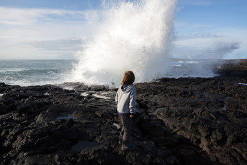 Children watching gig waves crashing in rocks on the south west coast on Iceland