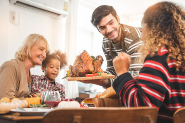 Thanksgiving Celebration Tradition Family Dinner Concept.family having holiday dinner and cutting turkey.Young black adult woman and her daughter happy.