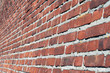 © AndreiNN - Large red brick wall. Side view. Perspective. The surface of the wall is slightly curved. Brickwork of a large number of bricks. Seams from a thick layer of cement mortar.