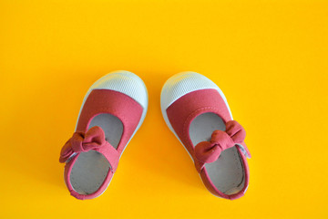 Pink shoes for children isolated on a yellow background.