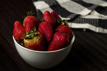 fresh strawberries over bowl and dark background